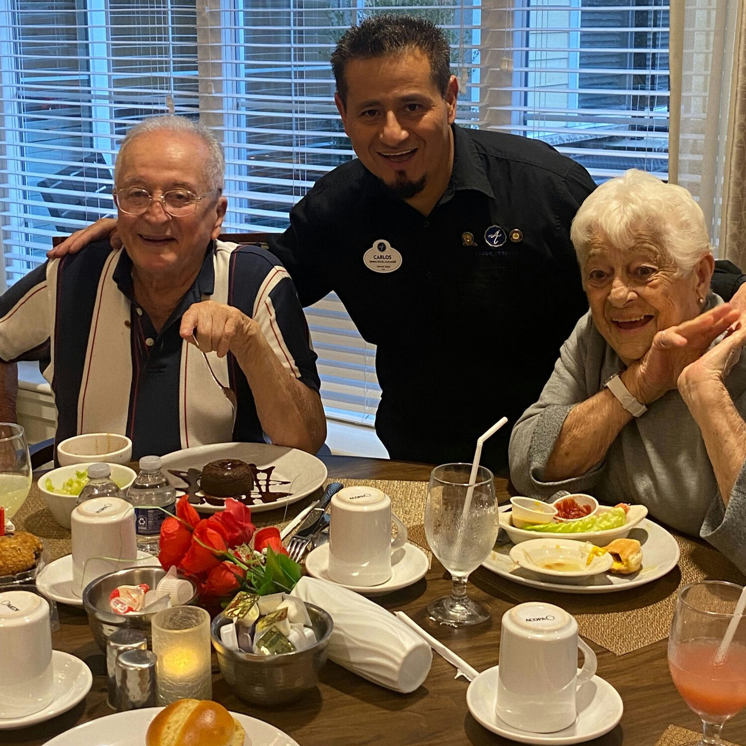 a senior couple taking a photo with a waiter after receiving their meals.