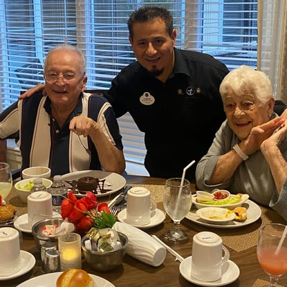 a senior couple taking a photo with a waiter after receiving their meals.