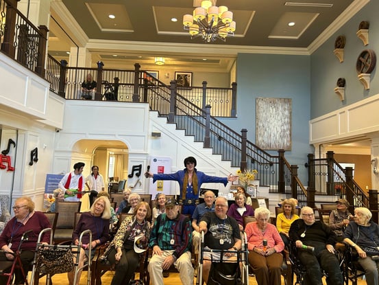 a group of senior residents taking a photo with an Elvis Presley impersonator