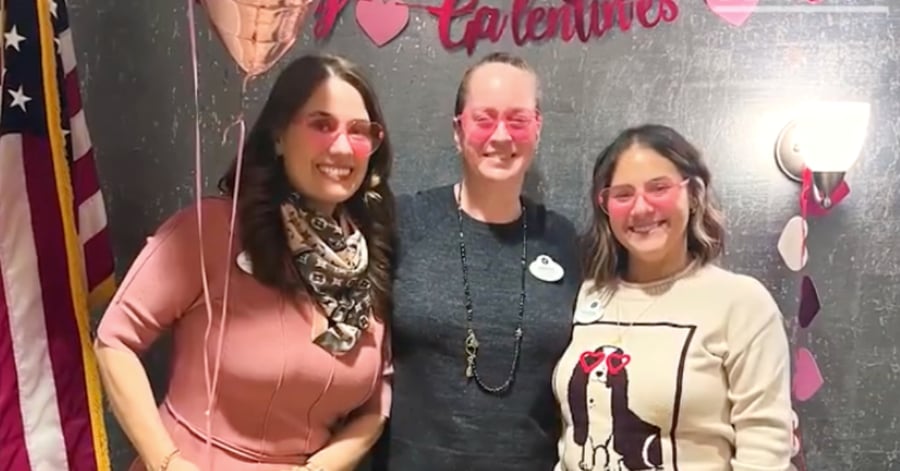 Three women smiling and posing together indoors, wearing casual clothing and accessories.