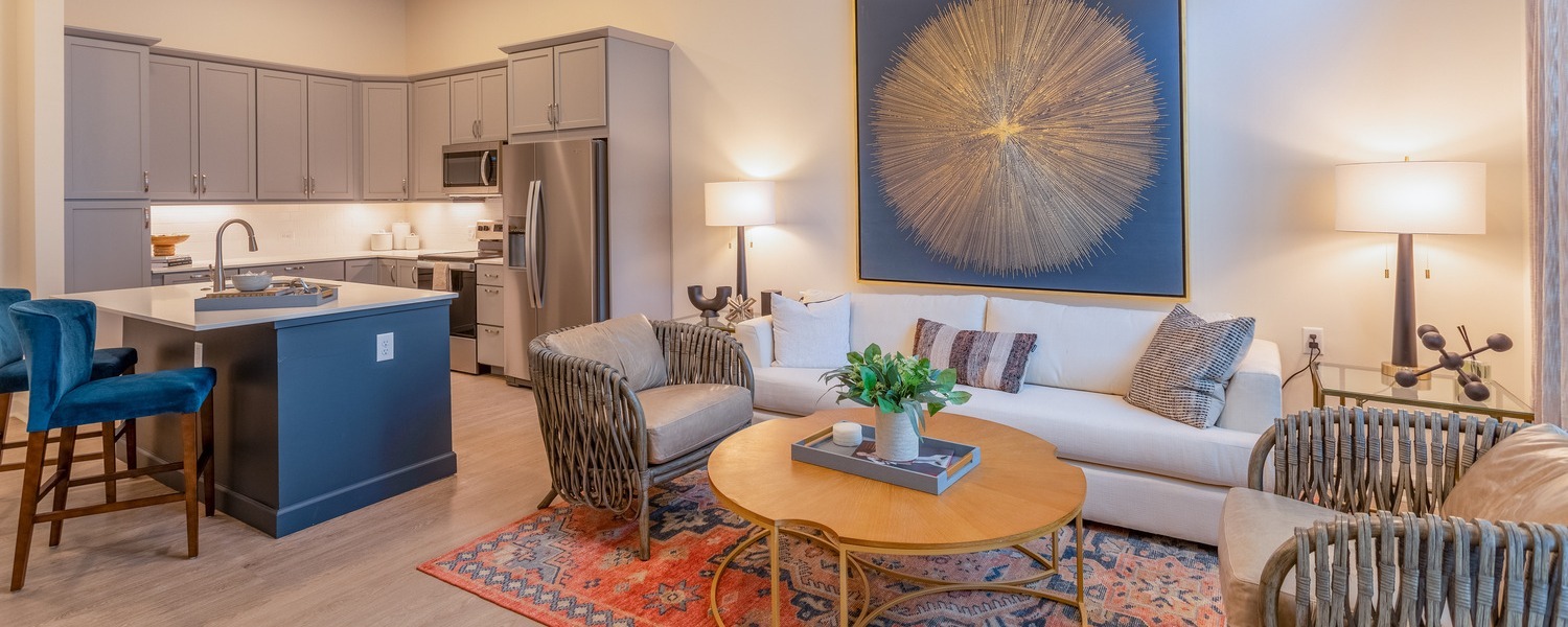 A stylish open-concept apartment at Opus East Memphis featuring a modern kitchen with island seating, warm living area with elegant furnishings, reflecting the upscale senior living East Memphis residents enjoy.