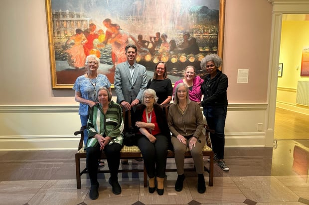 A group of residents and staff from this senior living community in Memphis, TN pose together in front of a large impressionist painting during a cultural excursion to a local art museum.