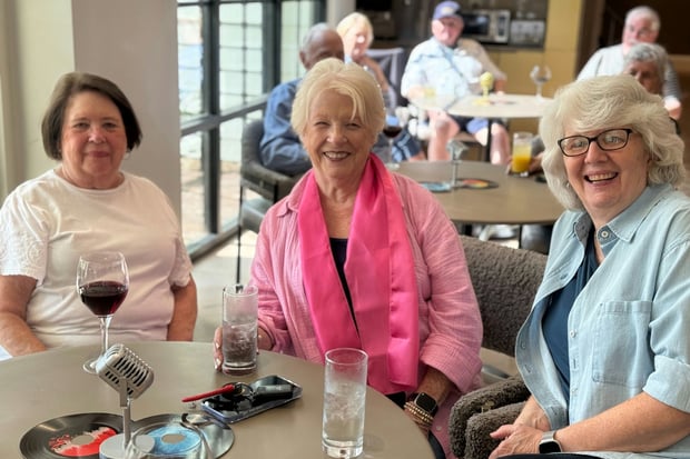 3 ladies from Opus East Memphis smiling around a table for happy hour