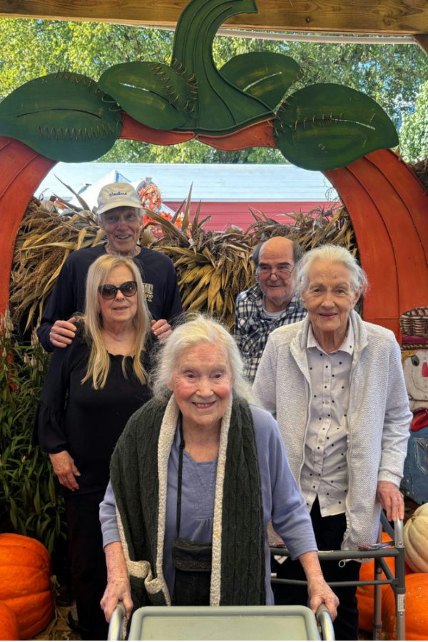 Opus East Memphis - a group of senior residents smiling in front of a fall-themed backdrop