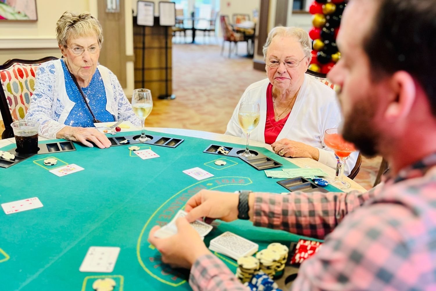 residents sit at a table and gamble/play cards