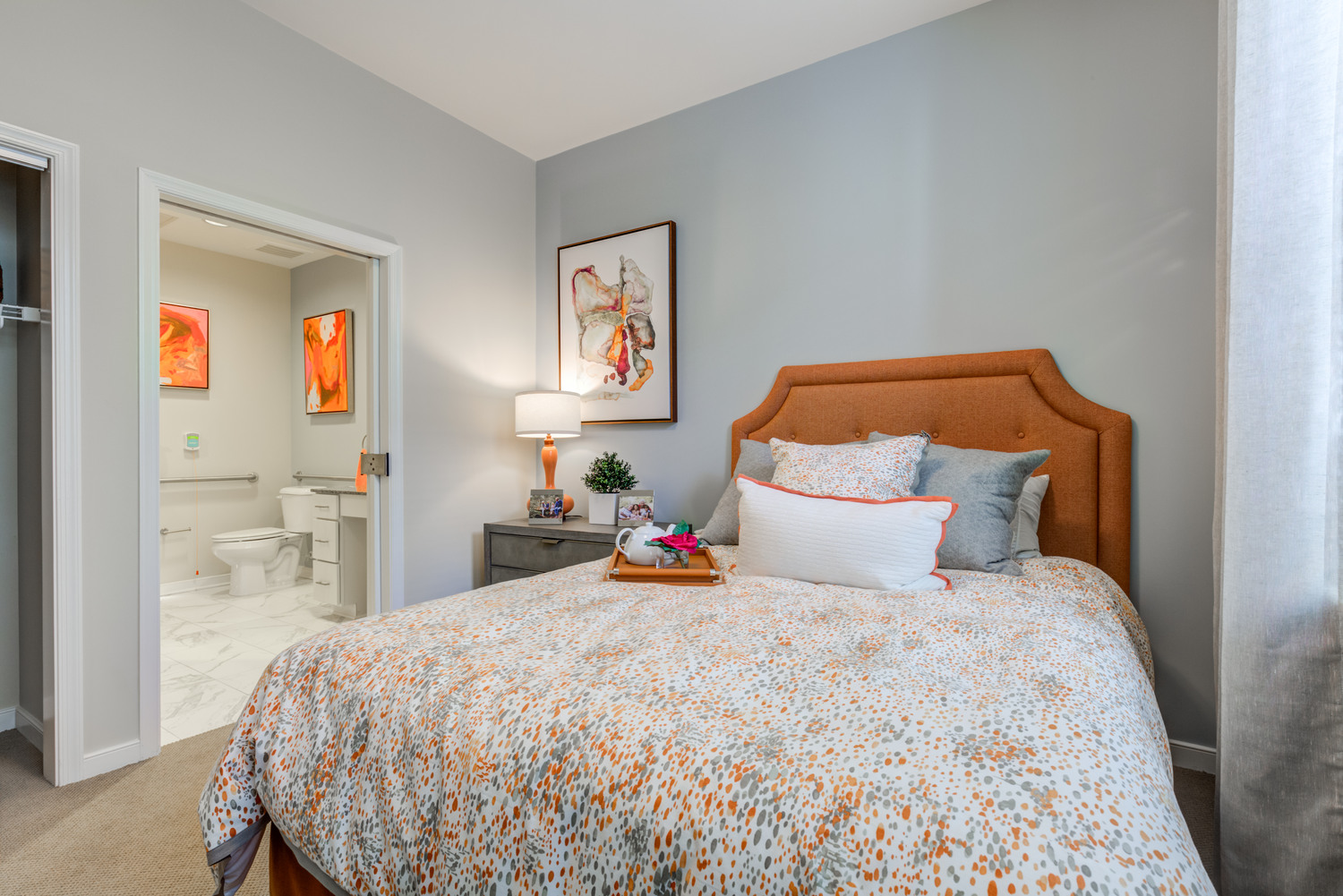 Cozy private suite at Arbor Terrace Prince William Commons with a plush upholstered headboard and ensuite bath, offering comfortable senior living in Woodbridge VA.