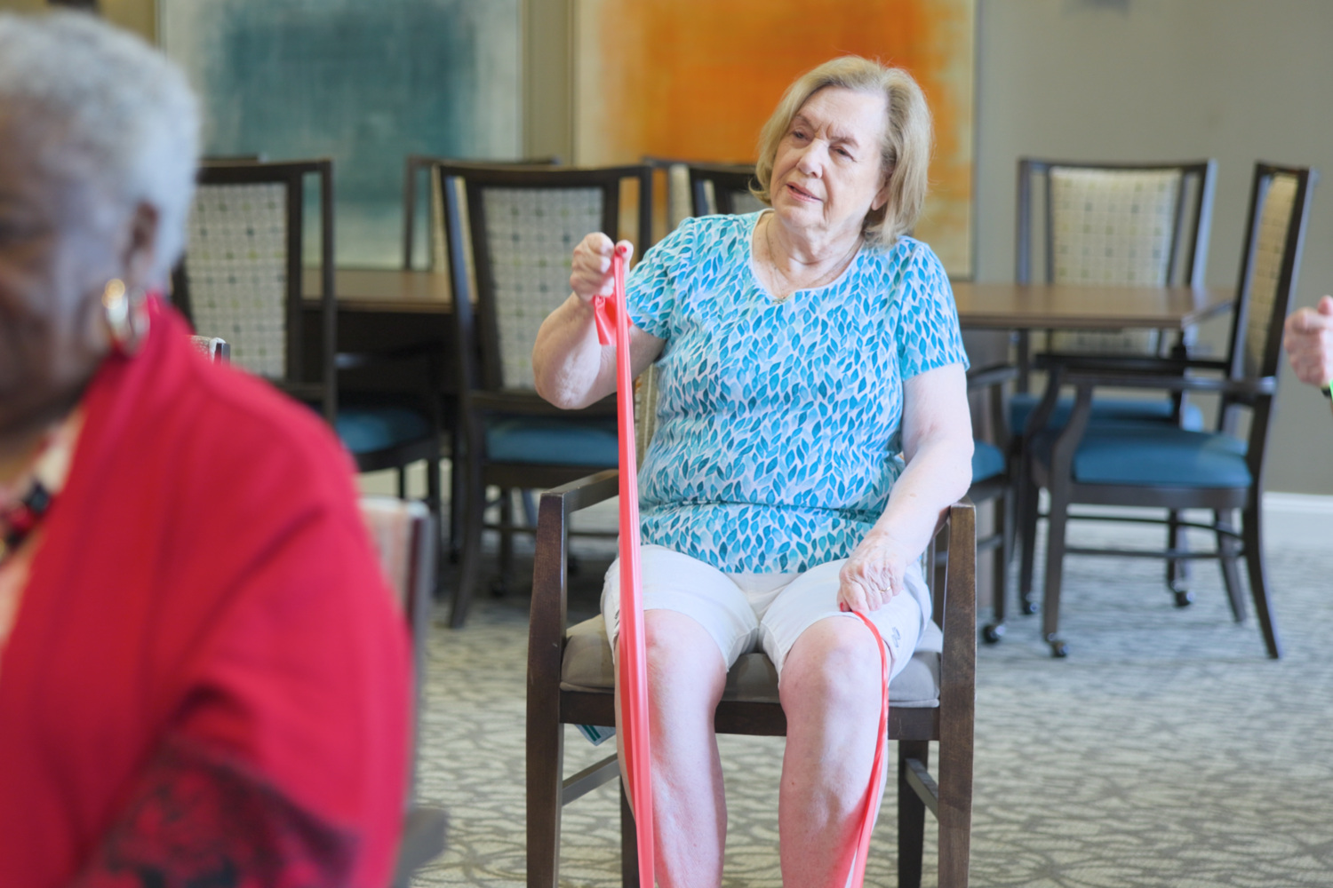 A resident stretches with a resistance band during a seated exercise class, reflecting the wellness-focused senior living Northern Virginia programs within this active senior community Prince William County setting.