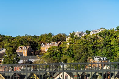 A scenic riverside town with charming rooftops nestled among lush green trees under a clear blue sky, capturing the historic charm near senior living Occoquan VA and the nature-access senior living Woodbridge lifestyle.