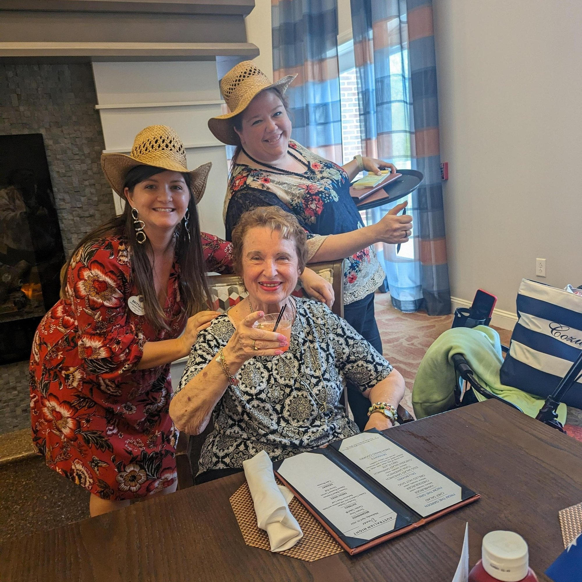 Resident enjoys a festive themed event with smiling staff members in cowboy hats, capturing the lively social calendar at Arbor Terrace Prince William Commons in Woodbridge VA.