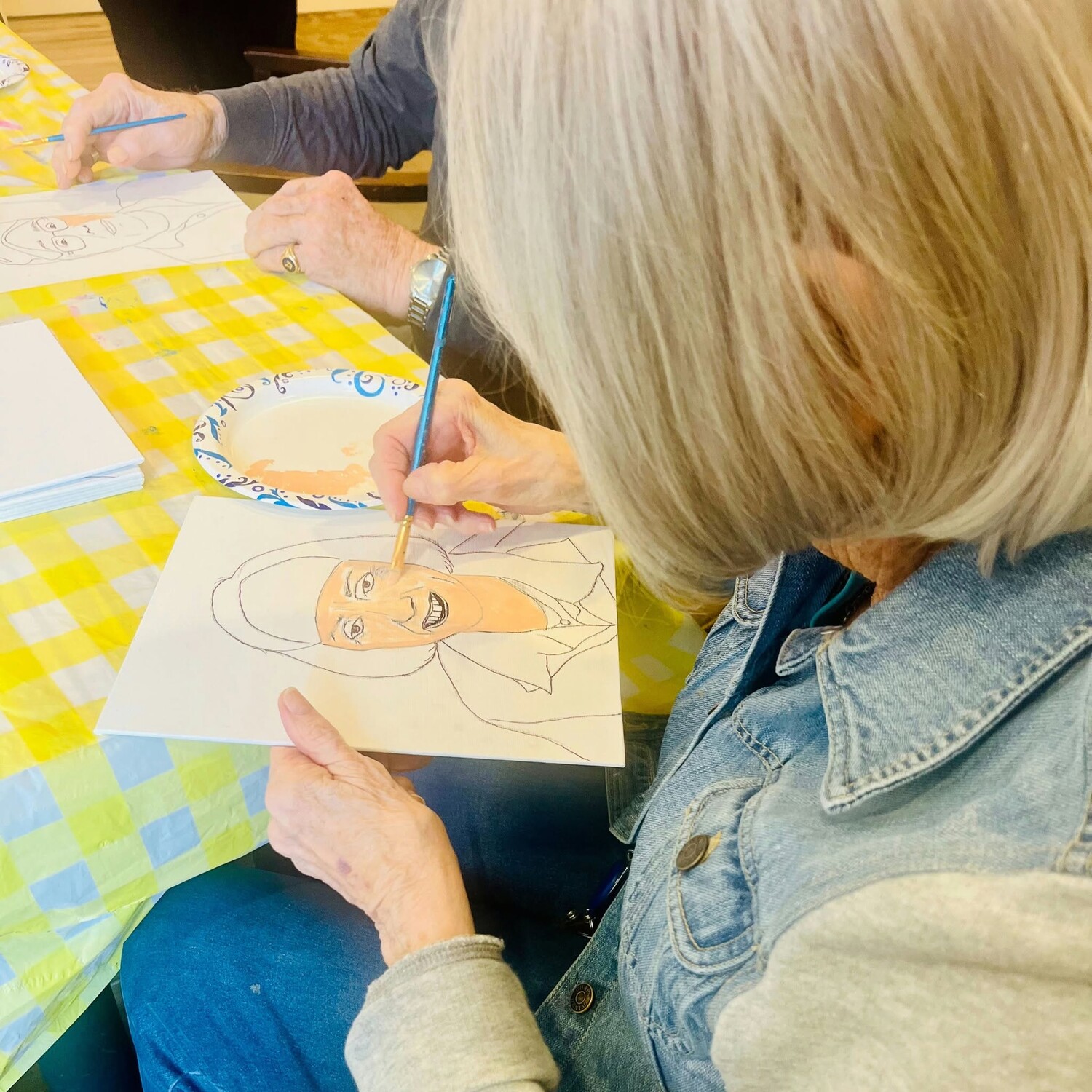 Residents paint colorful portraits together during a creative arts class, enjoying the vibrant community life of senior living Woodbridge VA, part of the engaging 55+ senior living Woodbridge lifestyle residents love.