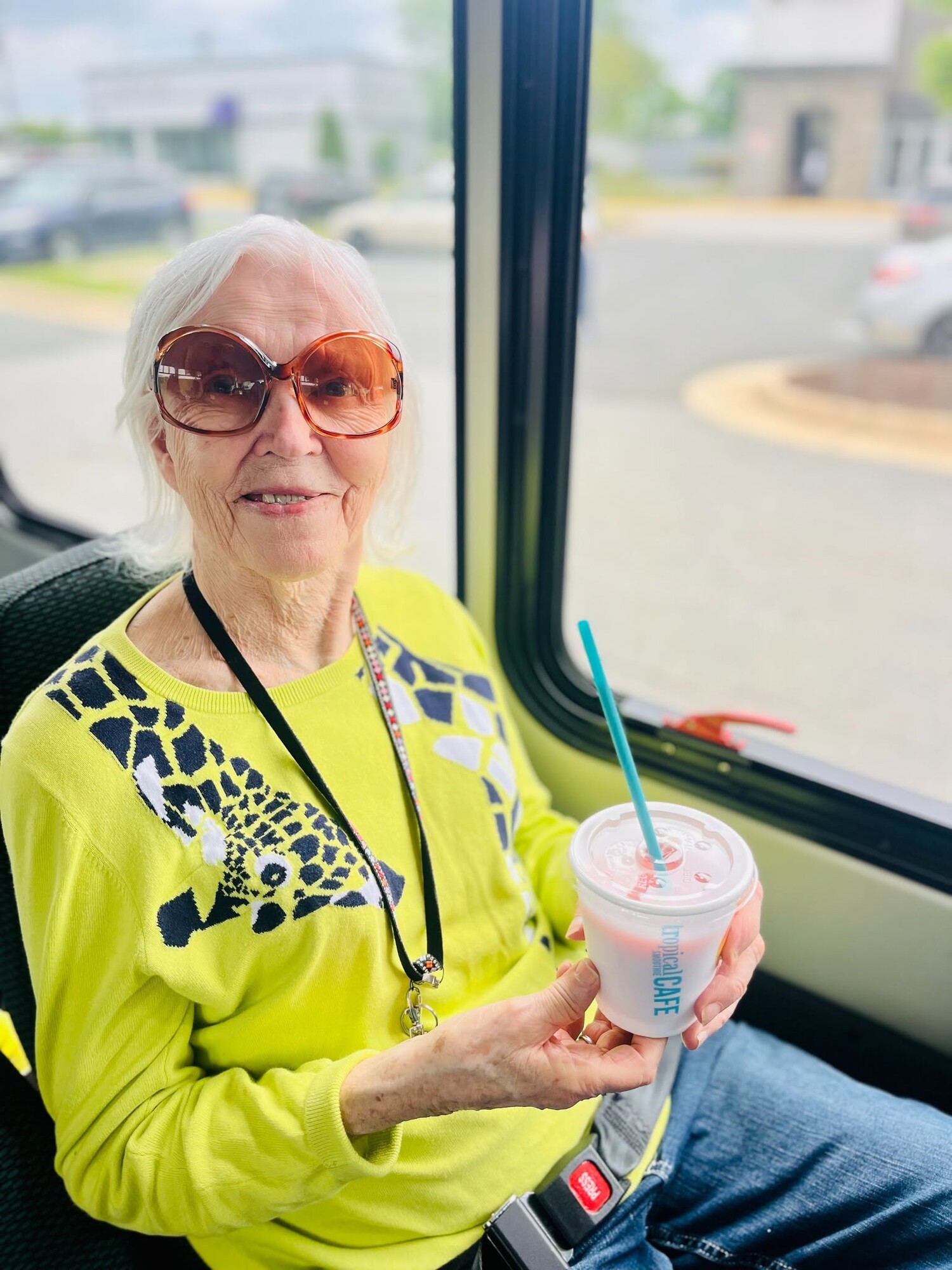 A resident smiles while enjoying a refreshing smoothie during a community outing on the shuttle, capturing the fun, active lifestyle of this active senior community Prince William County and senior living near Potomac Mills.