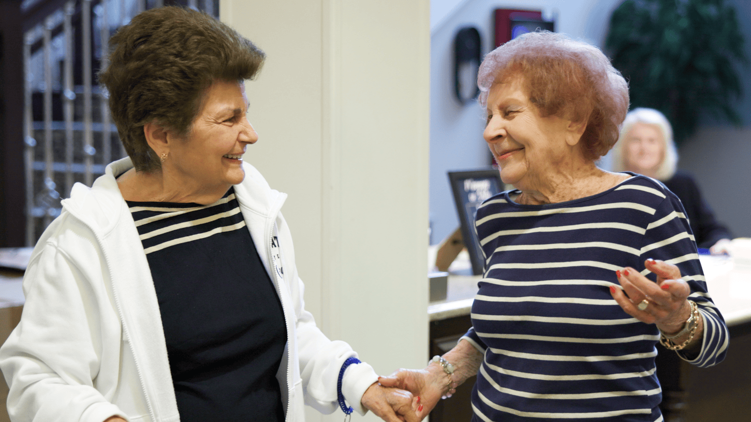 Two residents share a warm handshake and a smile during a community gathering, reflecting the friendly and welcoming atmosphere at our senior living community in Gambrills, MD.