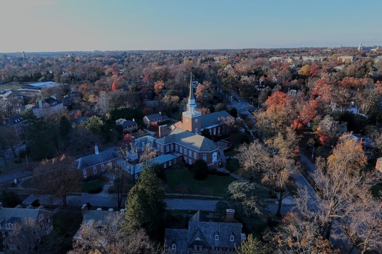 An aerial view highlights a peaceful neighborhood with a church steeple among autumn trees, reflecting the convenient senior living near Brookhaven, GA and Sandy Springs, GA.