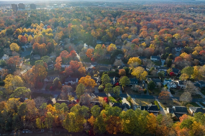 An aerial view reveals a vibrant neighborhood covered in autumn foliage, reflecting the connected charm of senior living near Dunwoody, GA and Sandy Springs, GA.