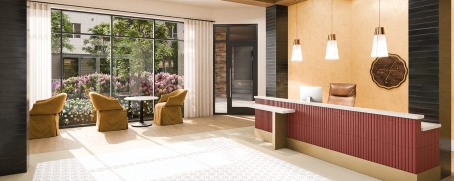 A bright reception lobby featuring plush armchairs, floor-to-ceiling windows, and a warm wood accented front desk, reflecting the inviting senior living in Sandy Springs, GA that residents and guests enjoy.