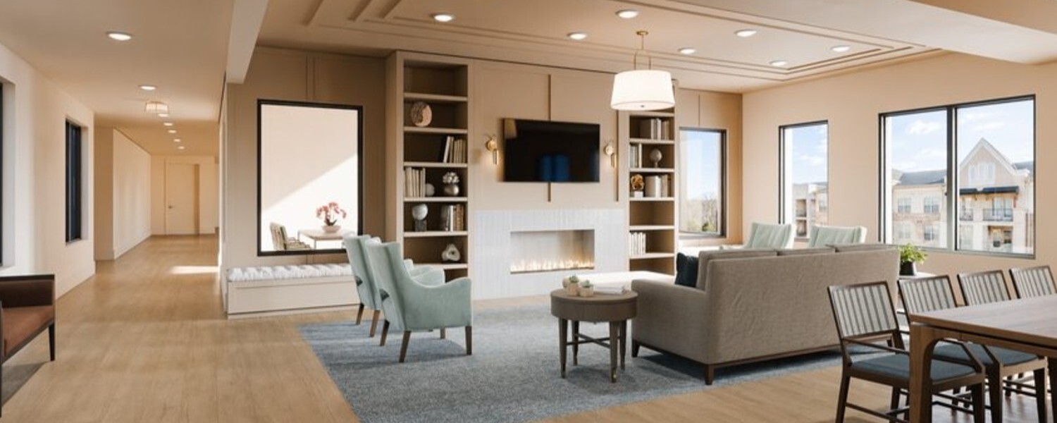 A spacious great room features a cozy fireplace, built-in bookshelves, and comfortable seating with large windows overlooking the community, showcasing the resort-style senior amenities in Sandy Springs, GA.