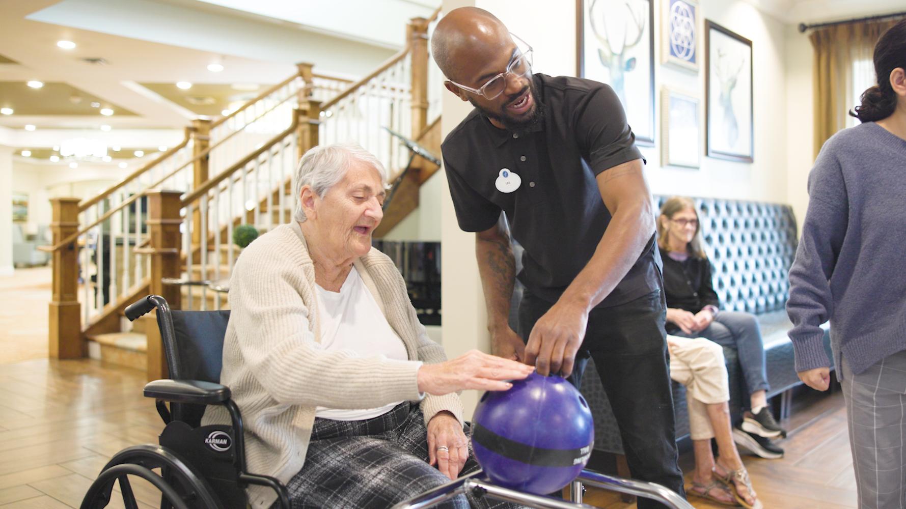 a senior lady and a male staff member playing bowling