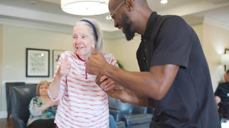 Resident and staff member dancing in the common room