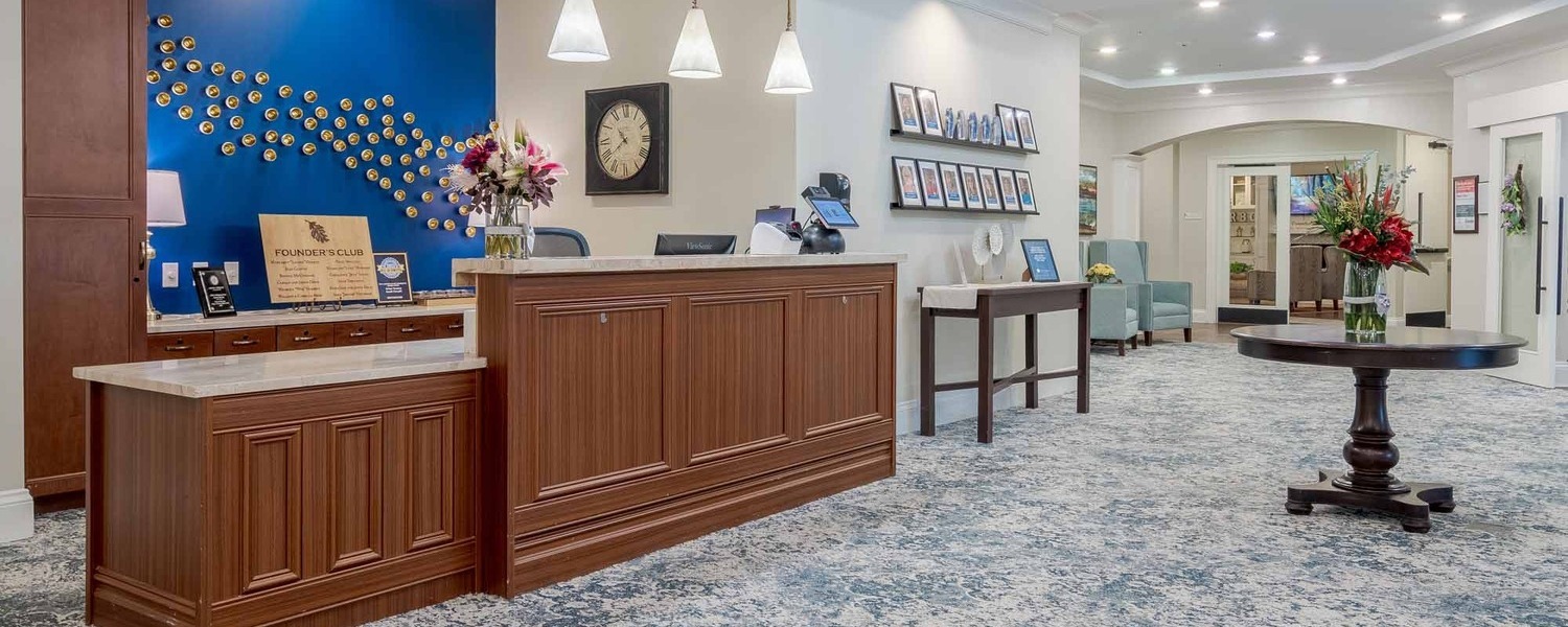 Elegant front lobby and reception area at Arbor Terrace South Forsyth, featuring warm wood finishes, fresh flowers, and welcoming decor at this senior living community in Suwanee, GA.