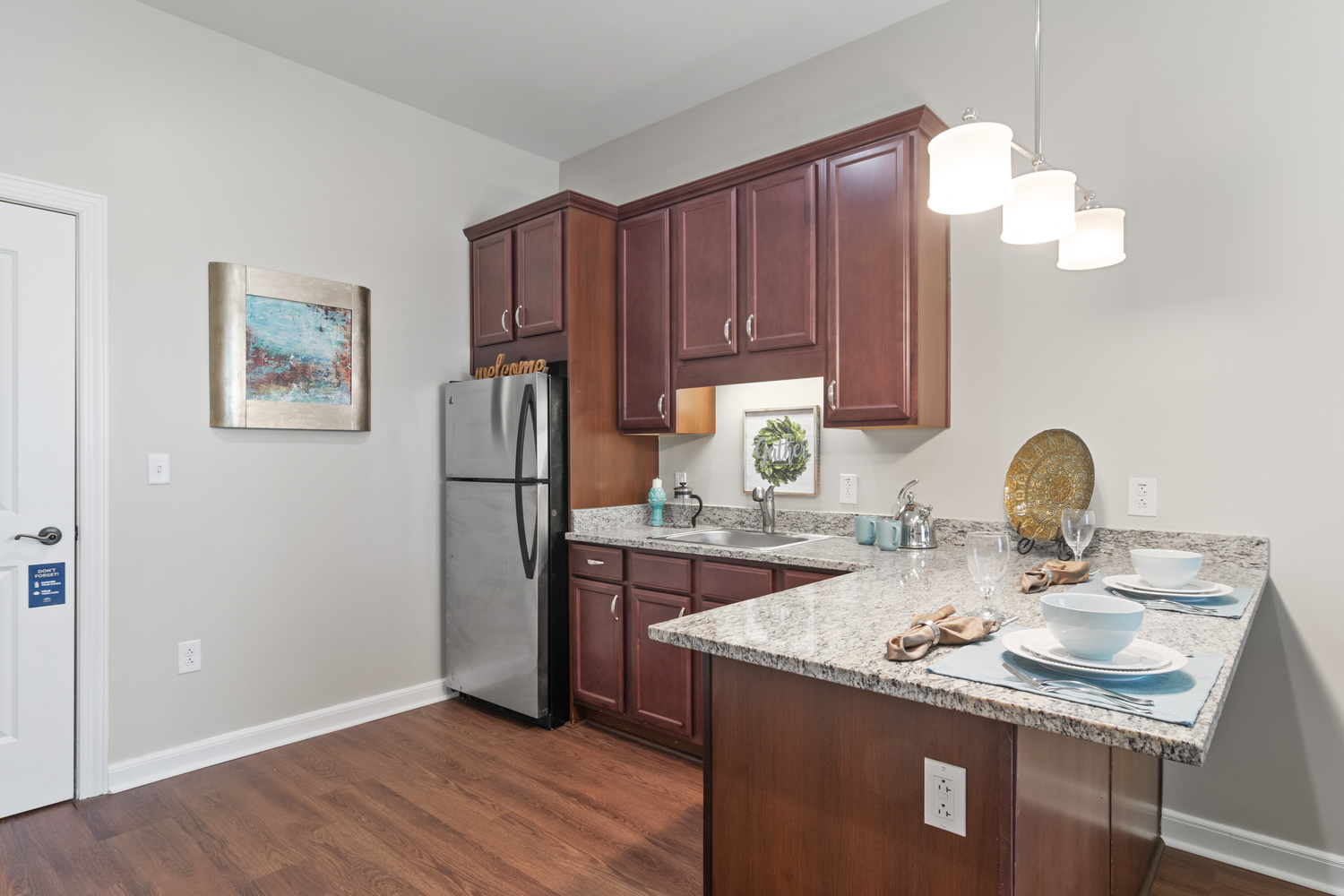 A well-equipped apartment kitchen with rich wood cabinetry, marble countertops, and stainless steel appliances at this senior living community in South Forsyth.