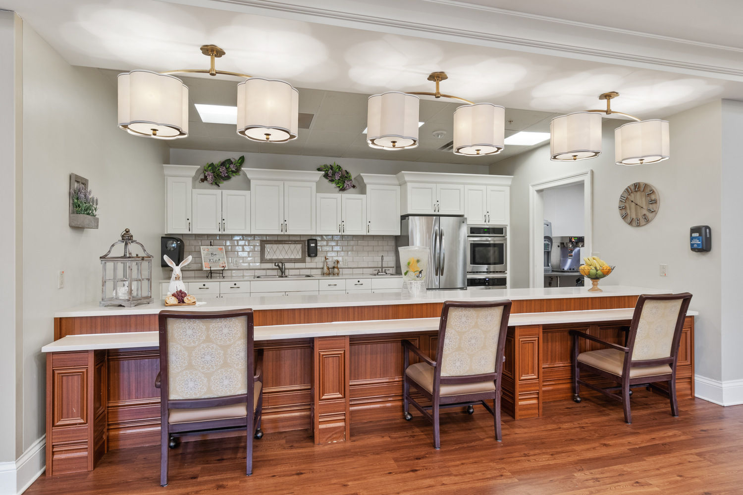 A bright, elegant bar and dining area with pendant lighting and warm wood tones at Arbor Terrace, a welcoming assisted living community in South Forsyth.