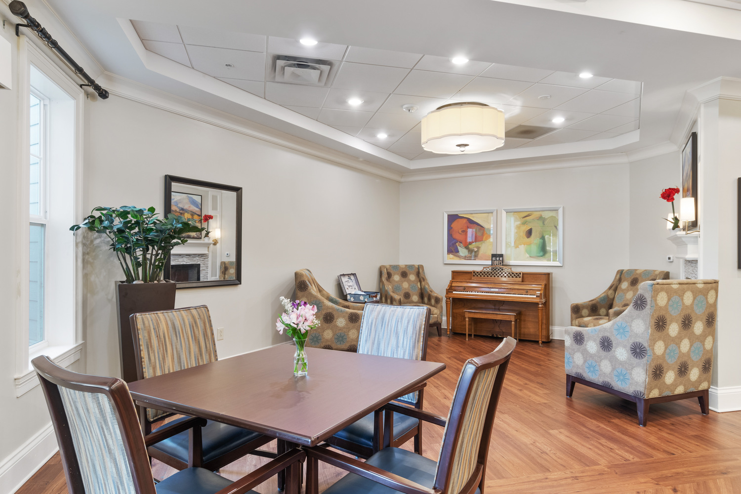 A cozy common sitting area with comfortable armchairs, a flat-screen TV, and warm decor at Arbor Terrace, an assisted living community in South Forsyth.