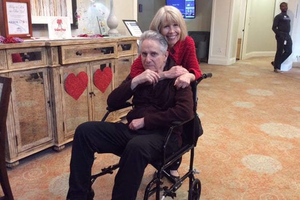 Two people pose warmly together during a Valentine's Day celebration in the decorated common area at Arbor Terrace South Forsyth, highlighting the festive seasonal events of senior living in Suwanee, GA.