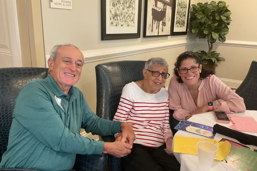 resident holds hands with family member while sitting at table