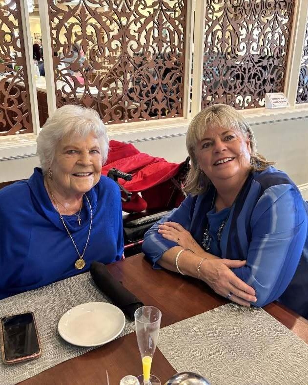 Two women share a warm, cheerful moment over a meal in an elegantly appointed dining area, enjoying the welcoming community atmosphere of senior living in Suwanee, GA.