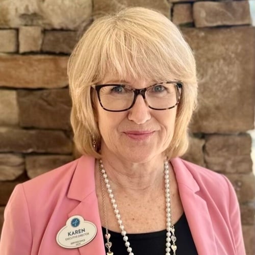 A staff member wearing a name badge smiles warmly in a professional headshot at Arbor Terrace South Forsyth assisted living community.