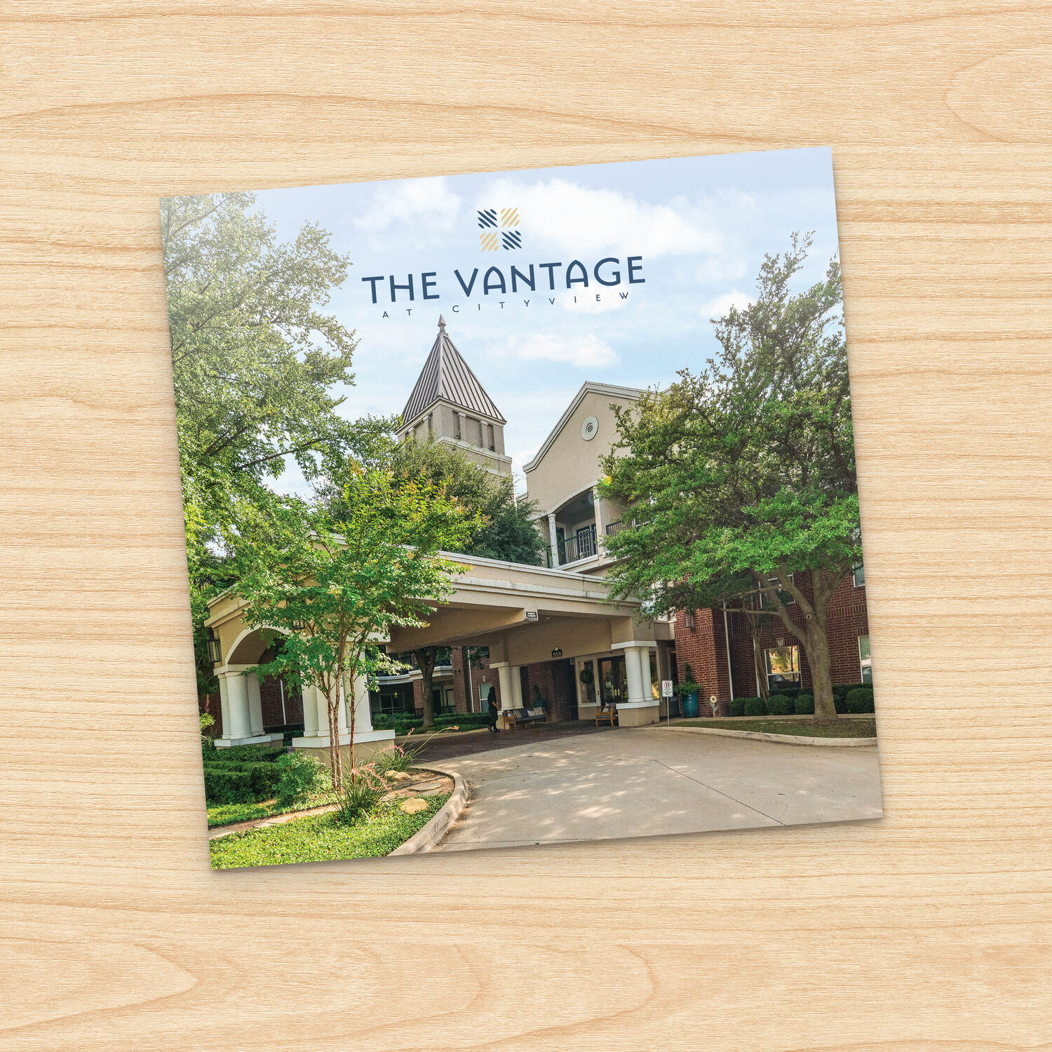 The Vantage at City View guide  cover on a light wood background, showing the community logo and a photo of the covered entry drive framed by green trees, a first look at this senior living community near parks and recreation in Fort Worth, TX.