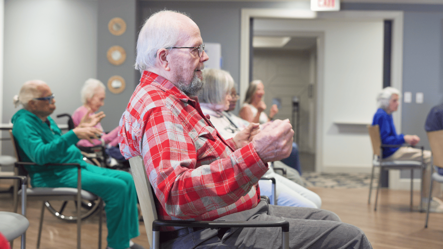 Residents enjoy a lively group activity session at Arbor Terrace Waugh Chapel, with one resident enthusiastically clapping along, reflecting the vibrant and engaging senior lifestyle programs at this community in Gambrills, MD.