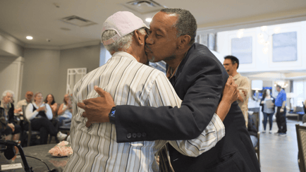 Male resident hugging a female resident and giving her a kiss on the cheek 