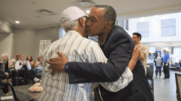 Male resident hugging a female resident and giving her a kiss on the cheek 