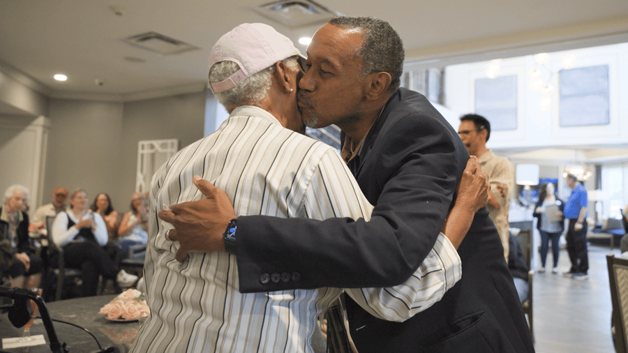 Male resident hugging a female resident and giving her a kiss on the cheek 