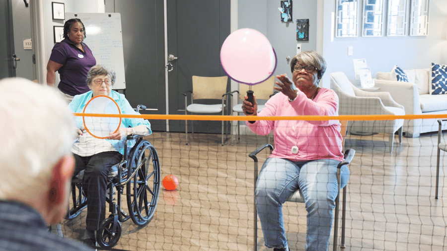 Residents playing chair volleyball with a pink ballon and net