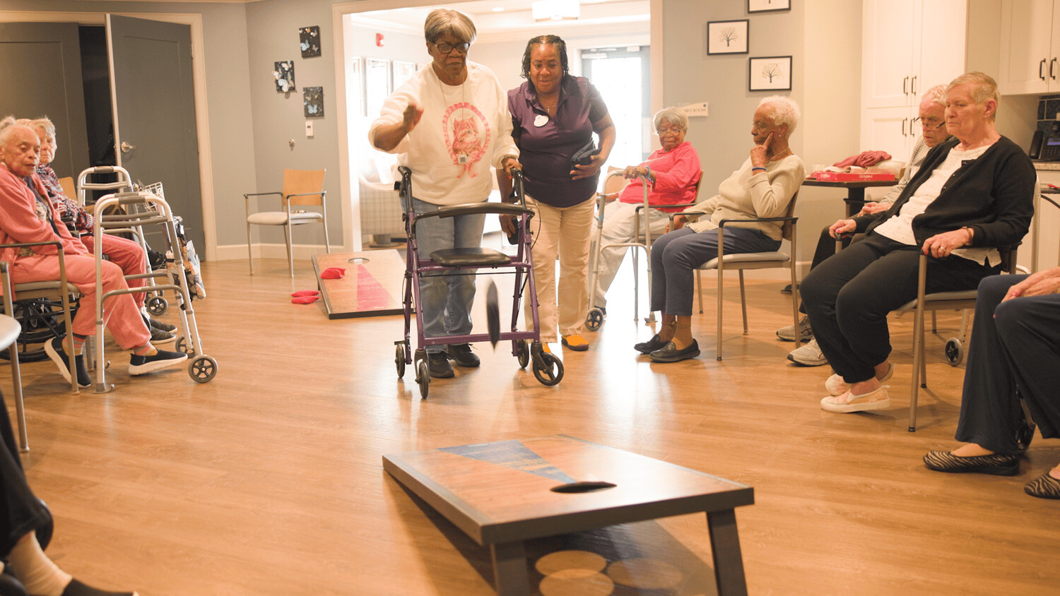 Residents enjoy a lively cornhole activity in a bright common area at Arbor Terrace Waugh Chapel, highlighting the fun and engaging senior lifestyle programs that foster connection and wellness at this assisted living community in Gambrills, MD.