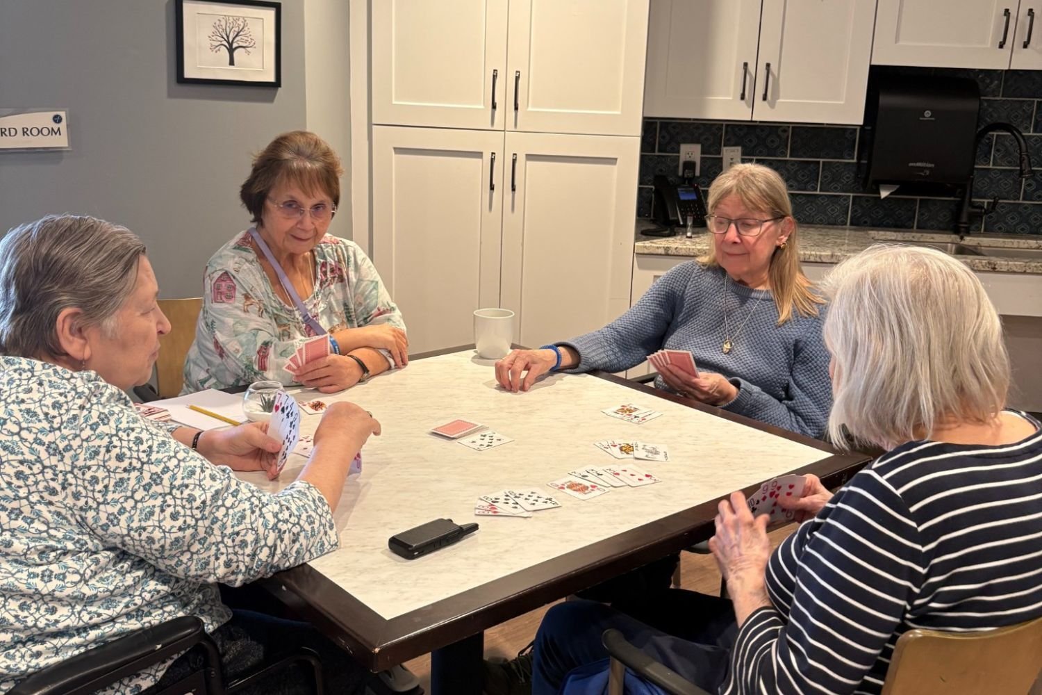 Residents enjoy a friendly card game together at a table at Arbor Terrace Waugh Chapel, highlighting the social and engaging lifestyle programs that foster connection and fun at this senior living community in Gambrills, MD.