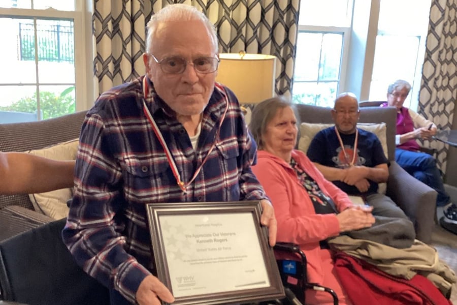 A resident proudly holds a veteran appreciation certificate while seated in a cozy common area, honoring those who served at our assisted living community in Gambrills, MD.
