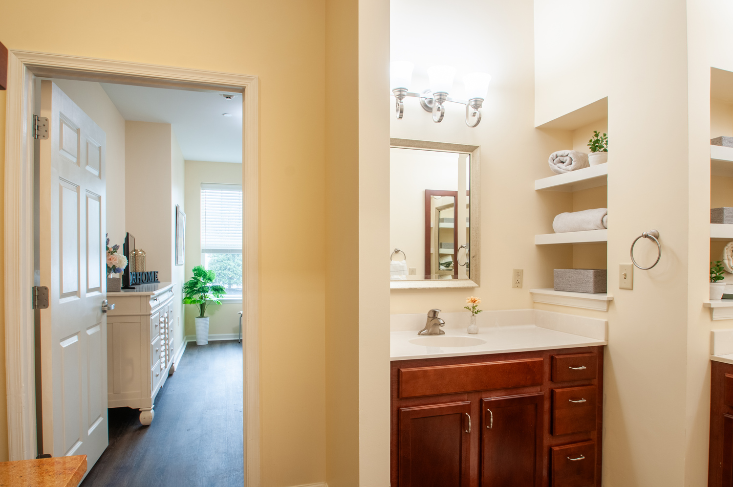 Senior living apartment bathroom and hallway view at Arbor Terrace Willistown in West Chester, PA, featuring built-in shelving and spacious layout.
