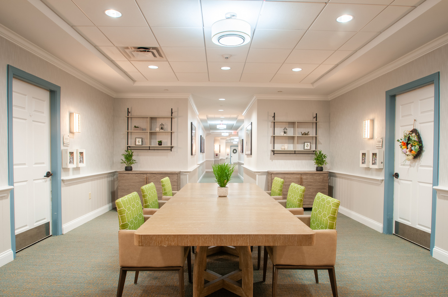 Bright gathering space with long table and green accent chairs at Arbor Terrace Willistown in West Chester, PA, designed for resident activities and social time.