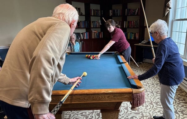 Resident and staff member playing pool in the activity room