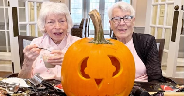 Arbor Terrace Willistown residents smiling with a carved pumpkin between them