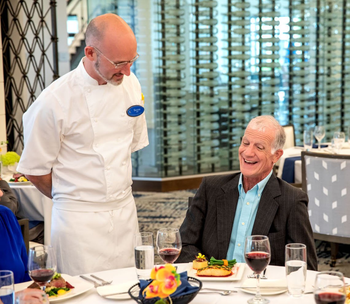 Chef checking in on residents having dinner and red wine