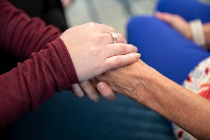 Two pairs of hands clasped together warmly, representing the compassionate, personalized care and support offered at a senior care community in Naperville, Illinois.