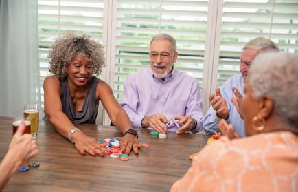 A lively group enjoys a friendly game of poker together, laughing and socializing around a table at a vibrant 55+ community in Suwanee, GA.