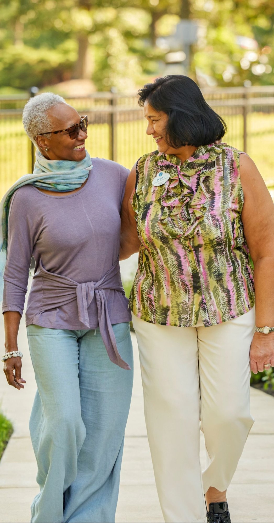 Residents and staff member walking outside on a sidewalk smiling at each other