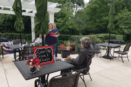 Residents and staff enjoy a Labor Day Trivia and Treats event on a lush outdoor patio at Arbor Terrace Herndon, highlighting the vibrant senior living with dining and activities Herndon VA and active senior living Herndon VA community life.