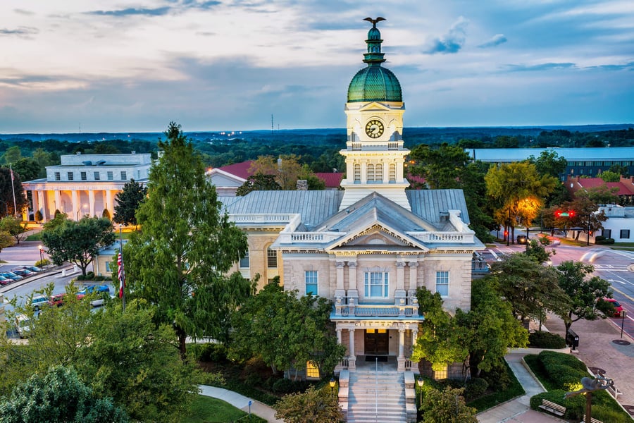 An aerial twilight view of a classic domed courthouse with a clock tower surrounded by mature trees in downtown Athens, GA, near senior living communities serving the Classic City and surrounding areas.
