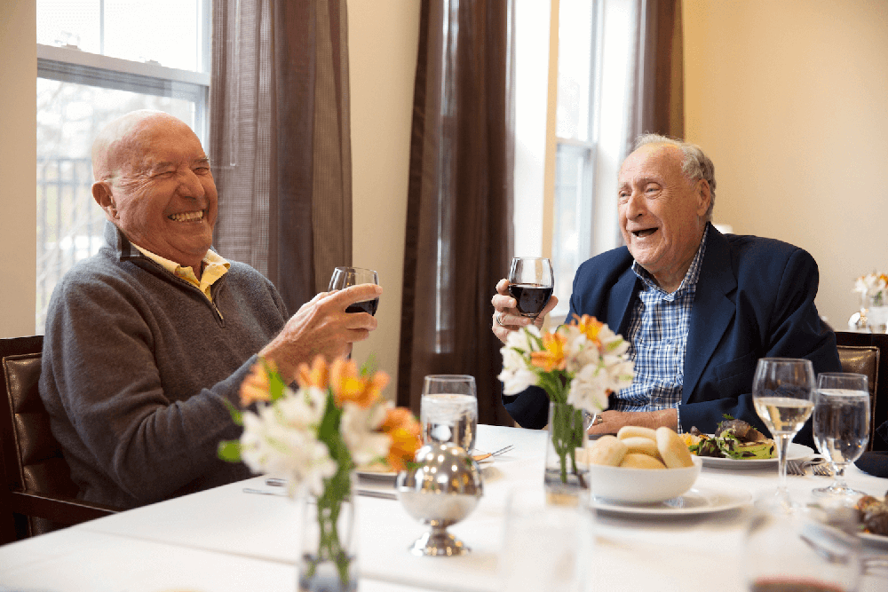 two senior citizens smiling with glass of wine